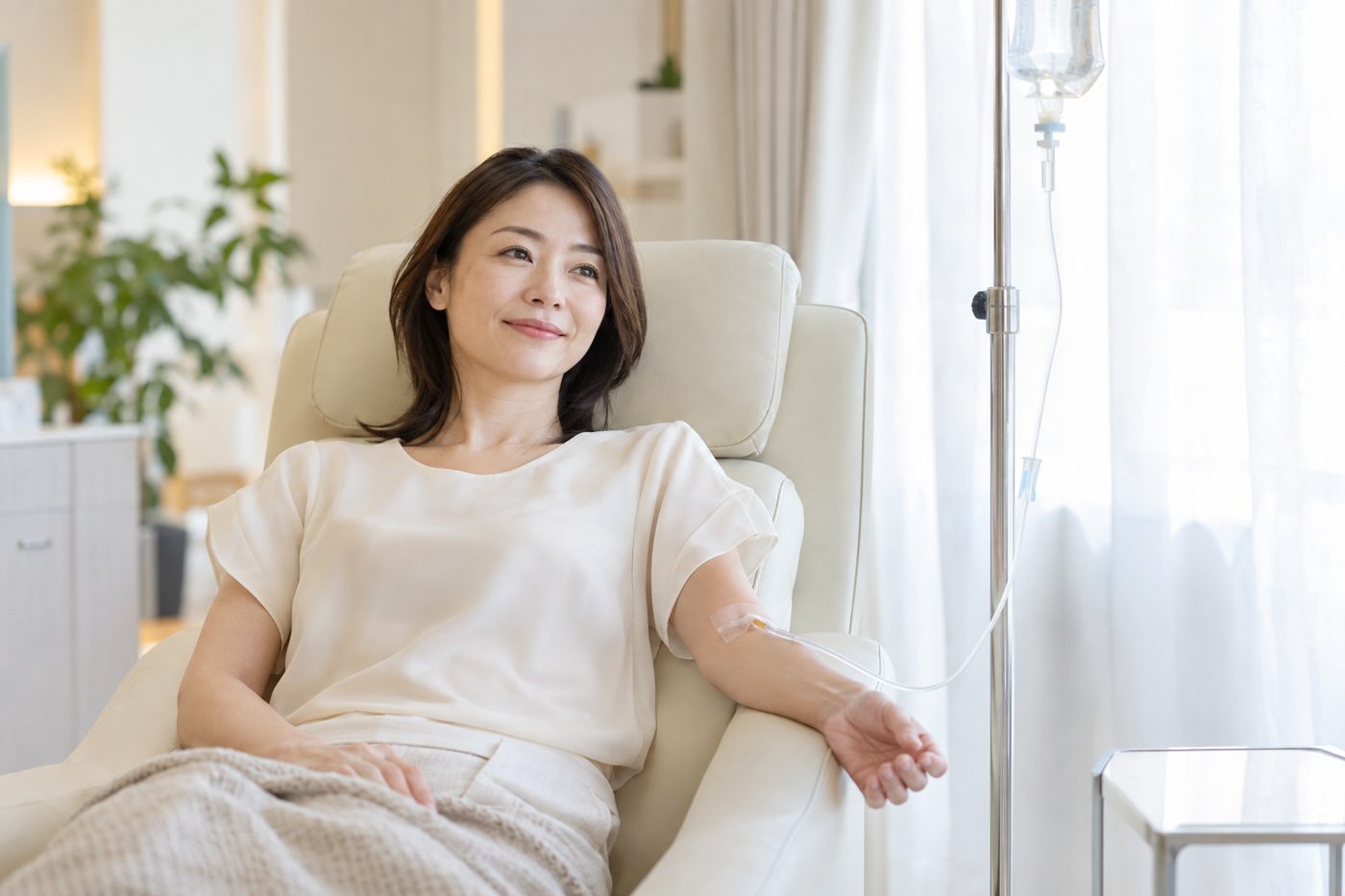 リクライニングチェアで点滴を受けながらくつろぐ女性